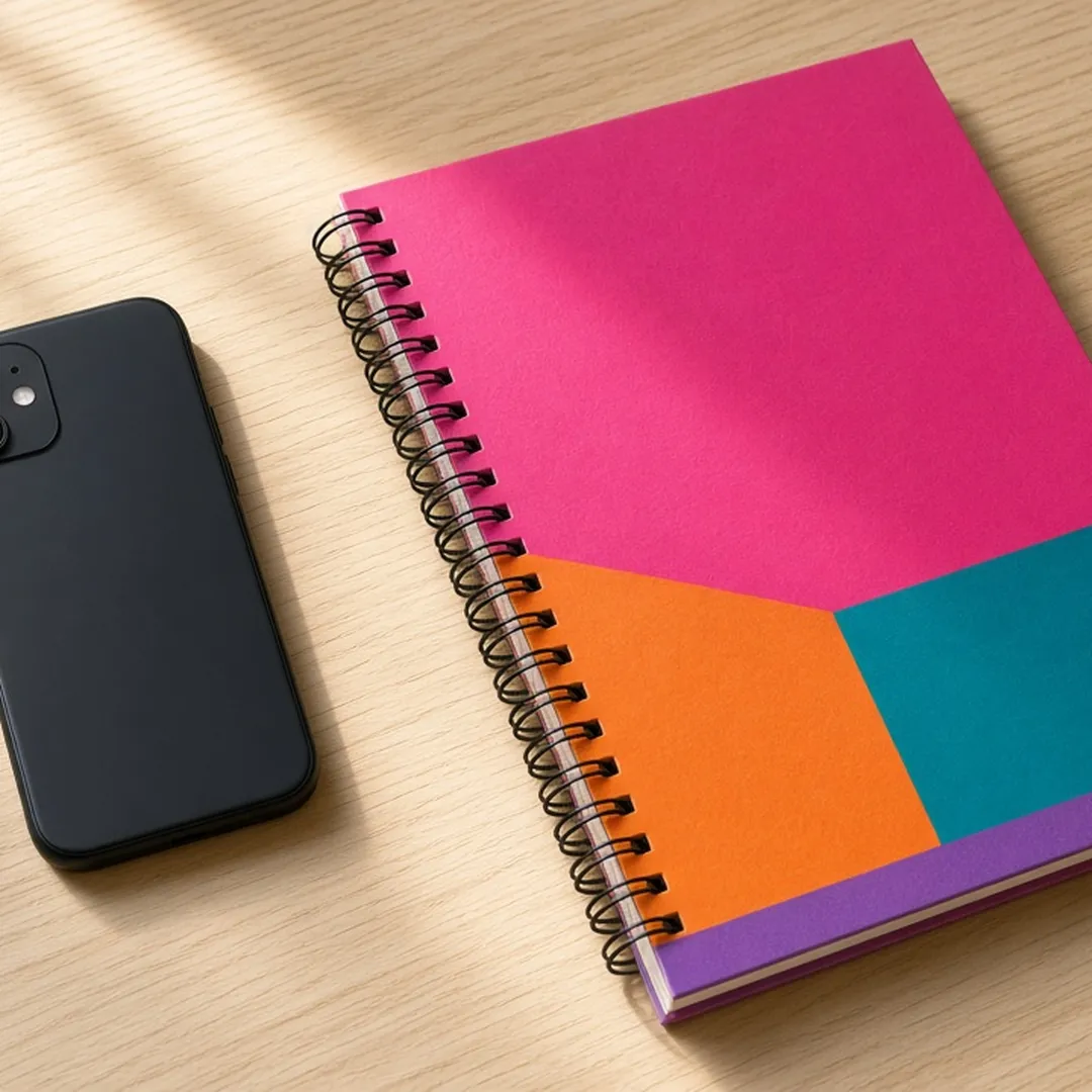 Smartphone resting face down on a table beside a notebook